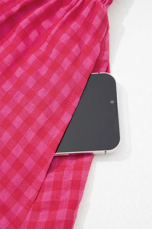 Cotton sundress with deep rose and pink gingham pattern, showing a side pocket holding a smartphone.