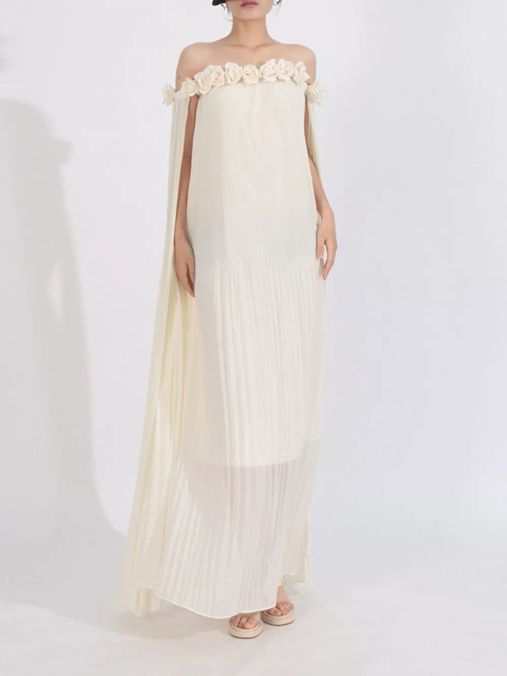 Elegant off-shoulder maxi dress in cream with floral appliques and cape sleeves.
