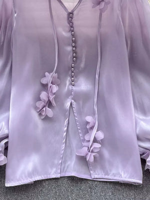 Purple sheer button-down shirt with delicate floral appliqué and bow details.