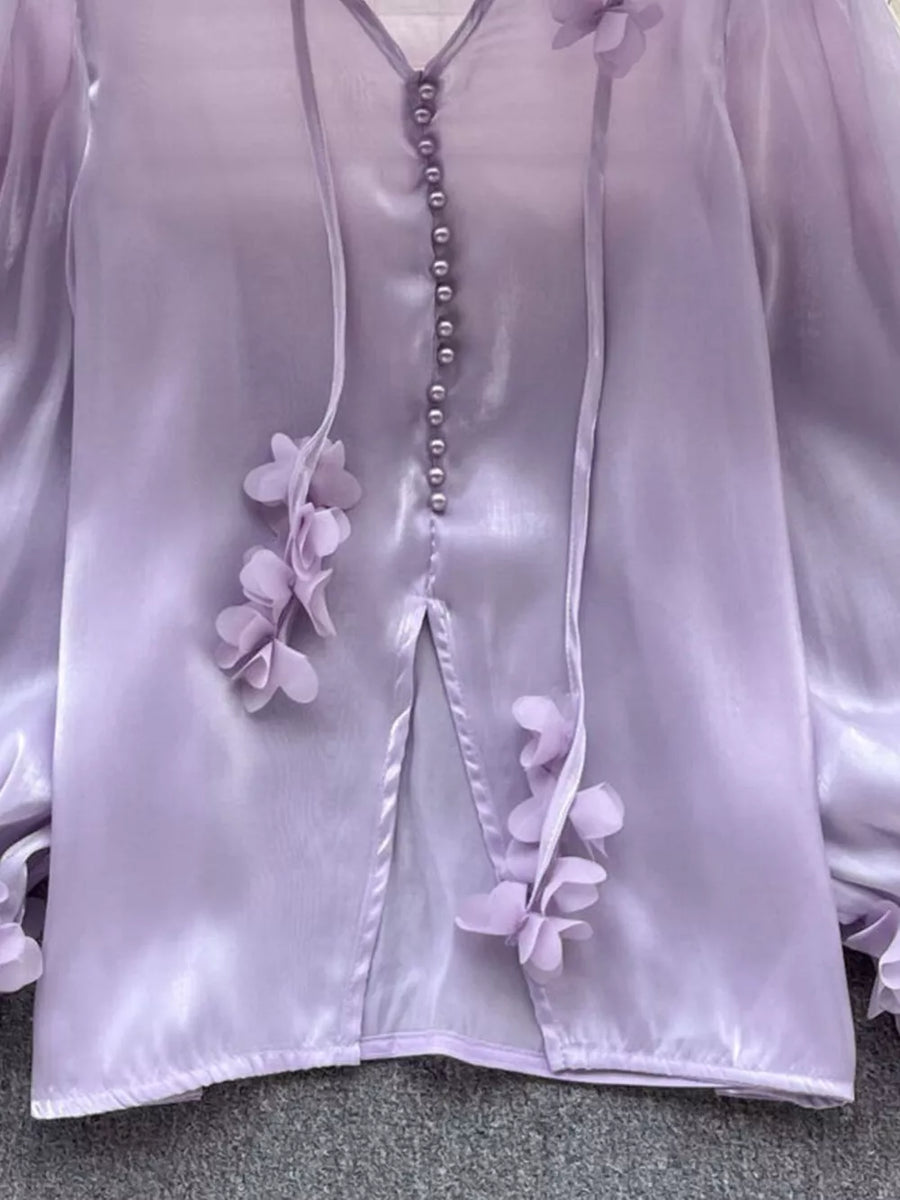 Purple sheer button-down shirt with delicate floral appliqué and bow details.