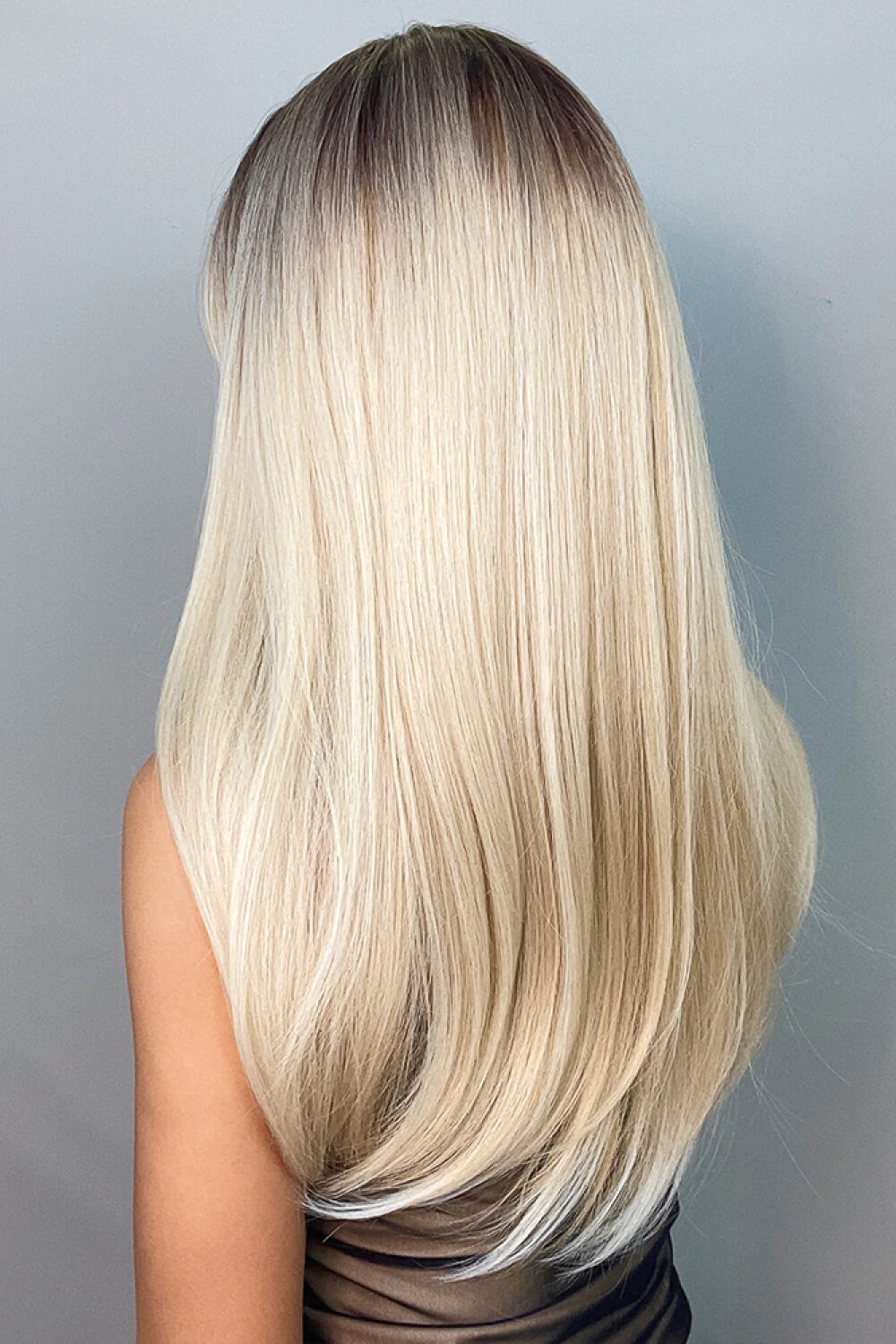 Ombre blonde long wig with dark roots and straight, layered blonde hair.
