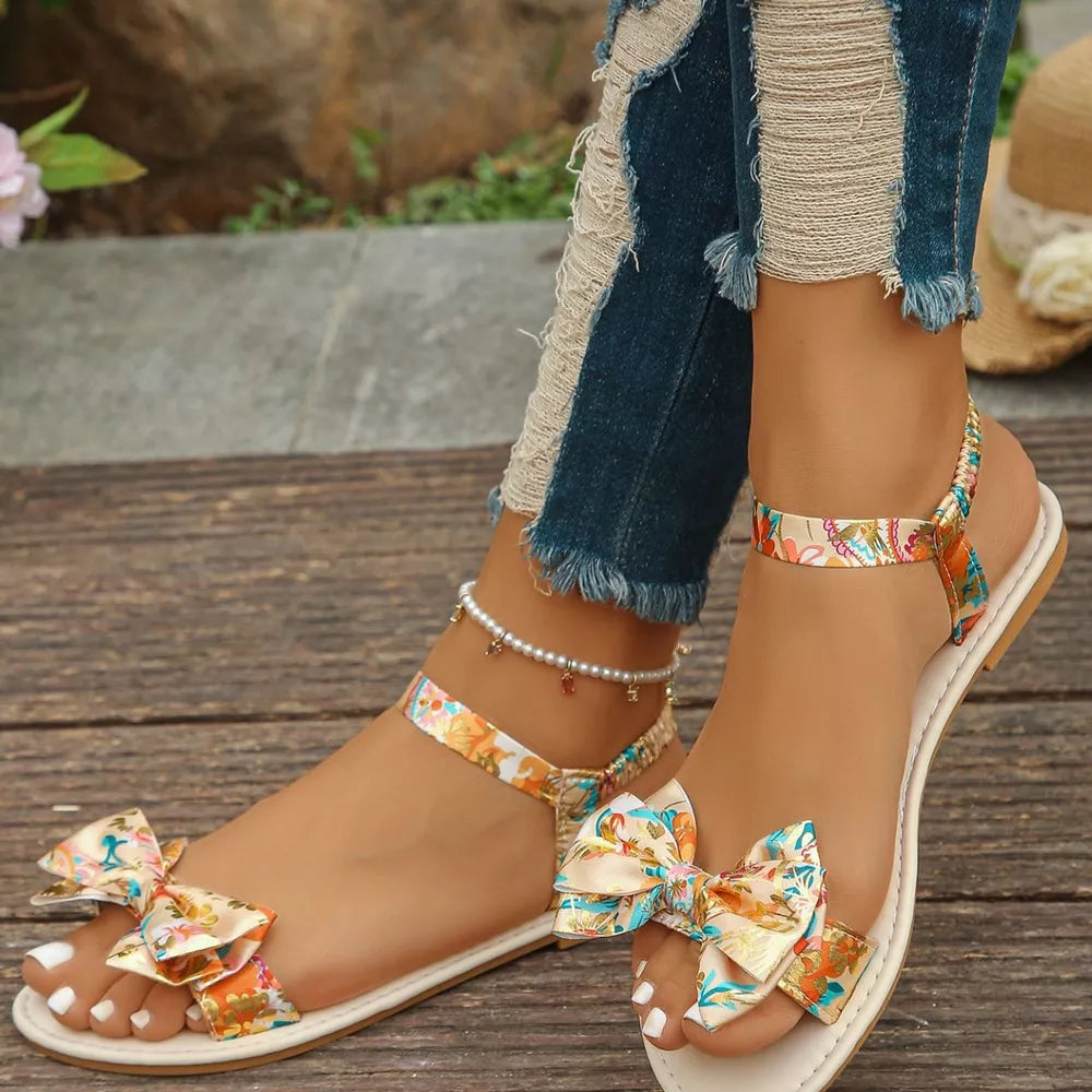 Floral bowknot flat sandals with ankle strap and pearl anklet.