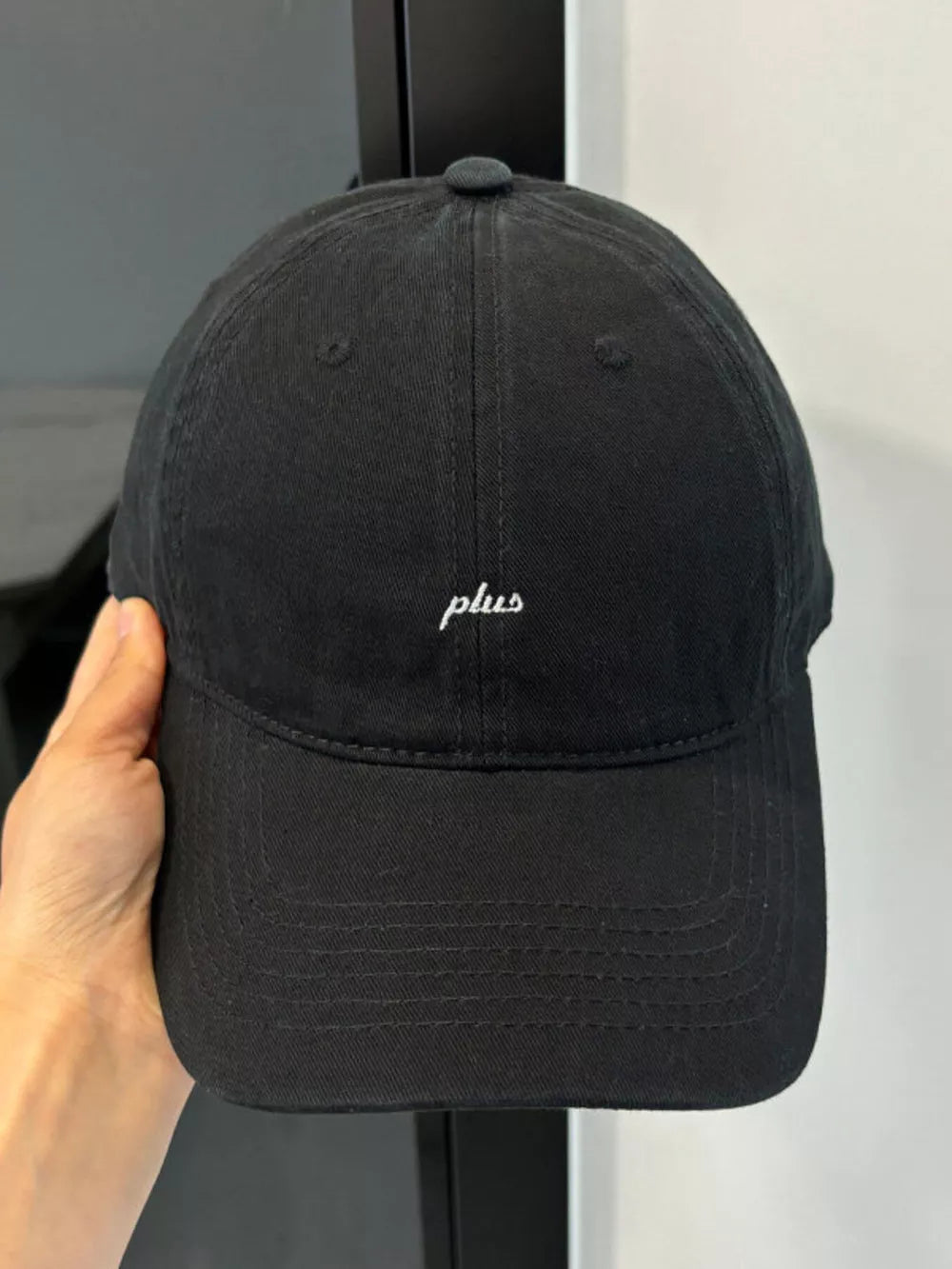Black baseball cap with embroidered white "plus" detail