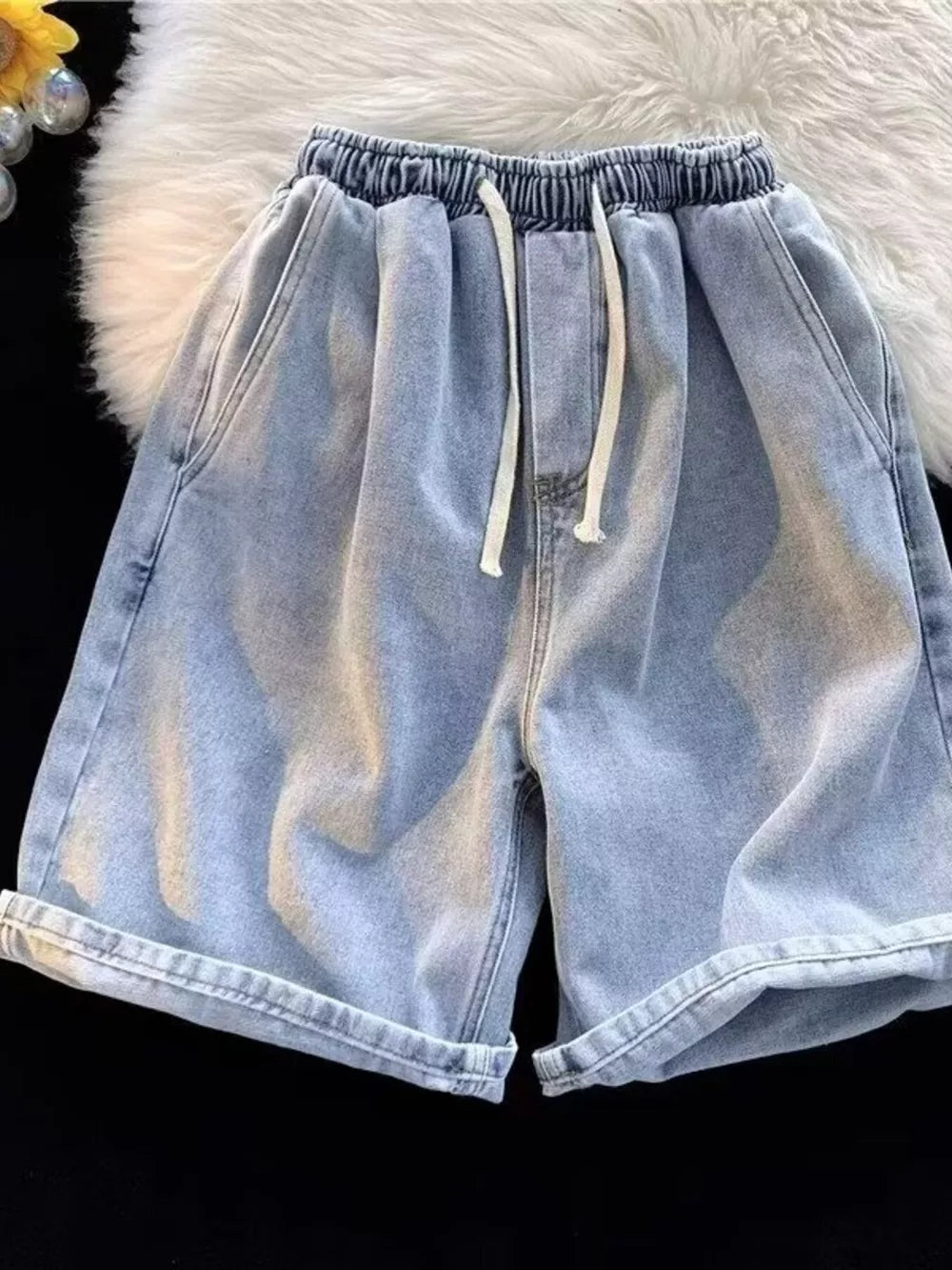 Men's light wash relaxed fit denim shorts with drawstring and rolled cuffs.
