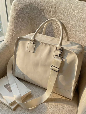 Cream PU leather travel bag with adjustable strap and top handles, perfect for toiletries.
