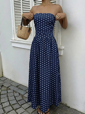 Navy polka dot A-line maxi dress with strapless neckline and cinched waist.