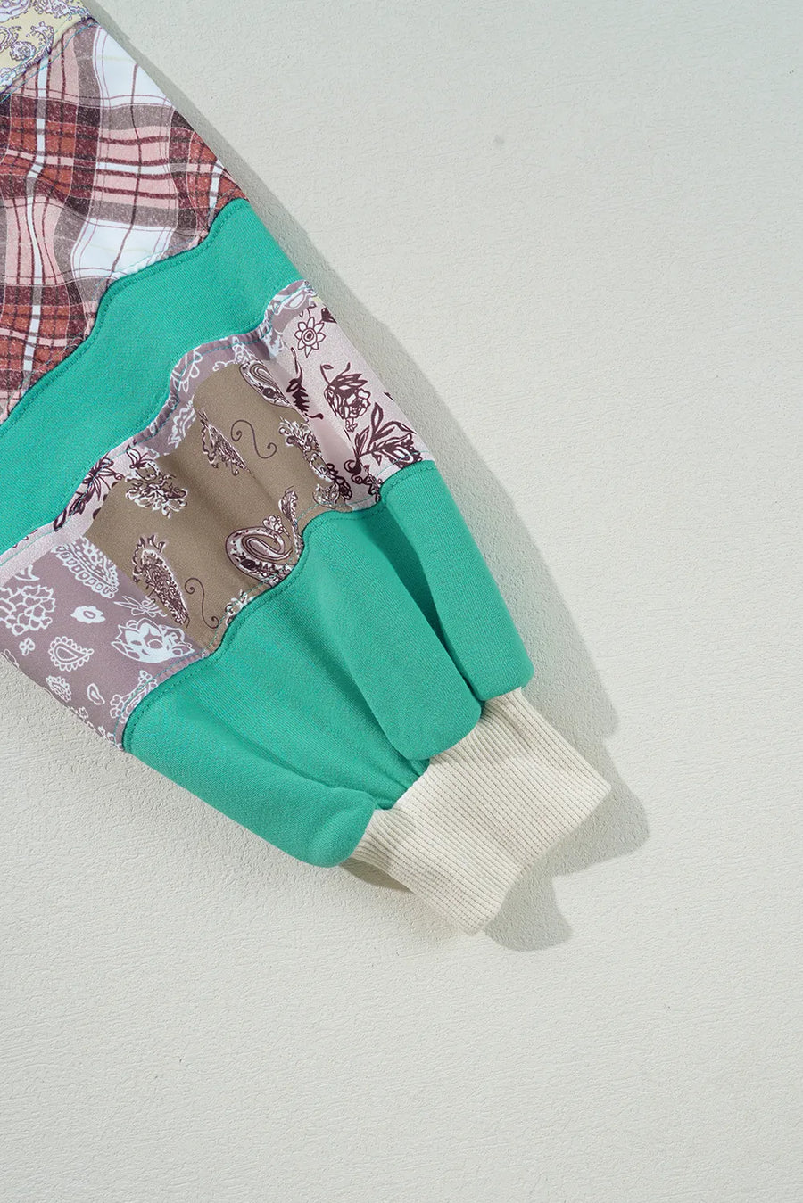 Patchwork raglan sleeve sweatshirt in turquoise with plaid and paisley patterns, ribbed cuff.