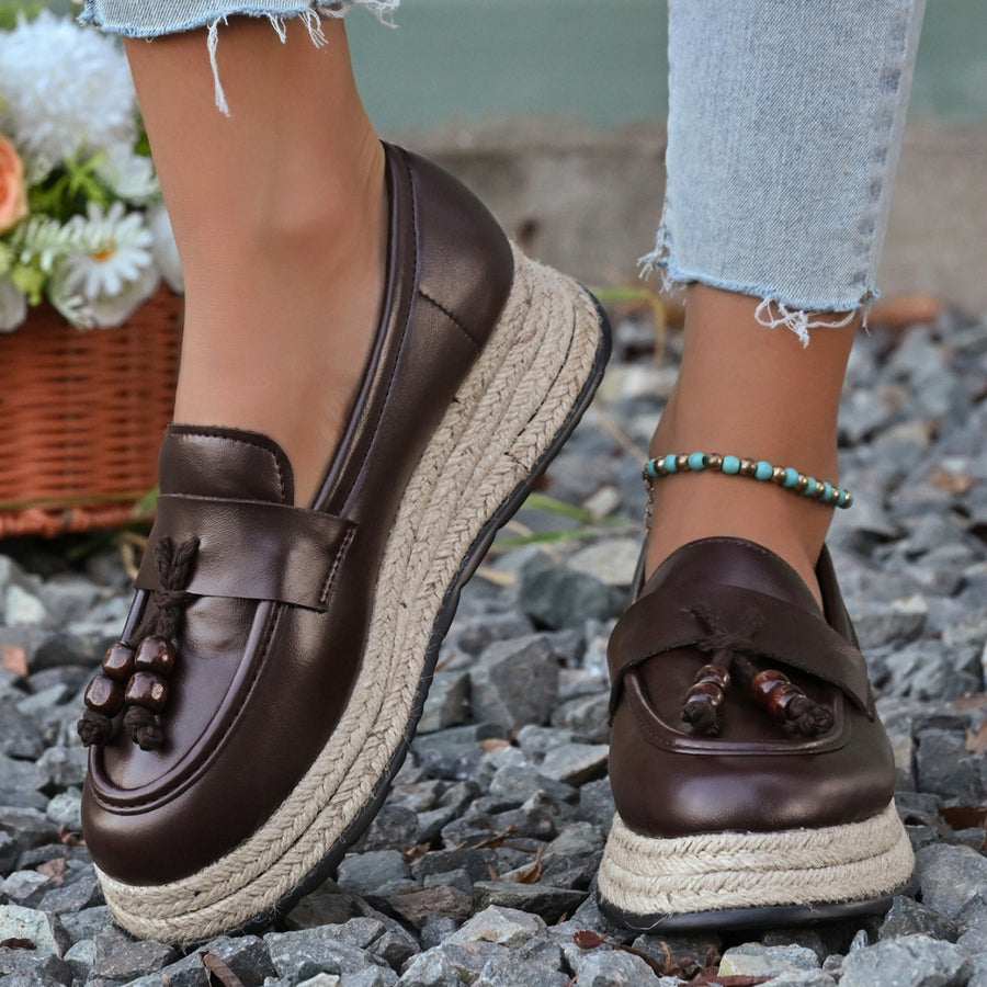 Brown espadrille wedge slip-on loafers with braided jute sole and tassel detail.