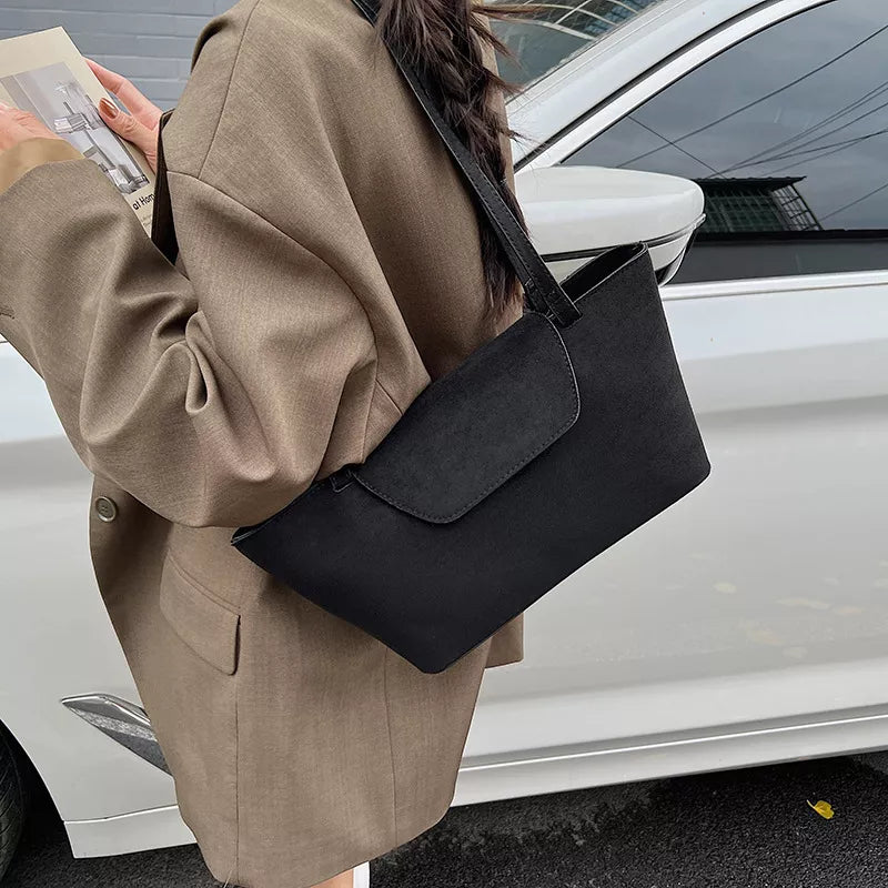Black suede flap tote bag with clean lines and a single shoulder strap.