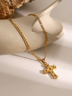 Gold cross pendant necklace with figaro chain, featuring zirconia accents.