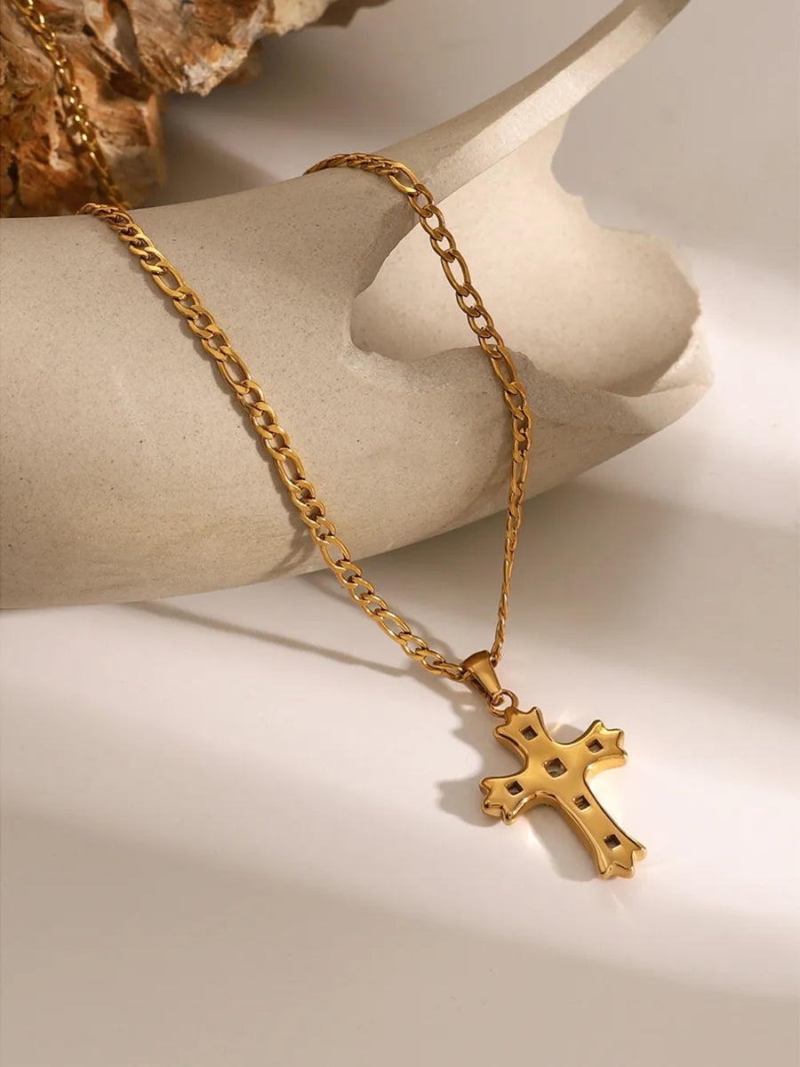 Gold cross pendant necklace with figaro chain, featuring zirconia accents.