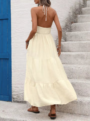 Cream halter neck maxi dress with smocked waist and tiered skirt.