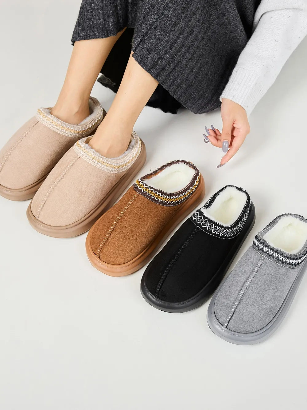 Embroidered trim shearling house slippers in tan, caramel, black, and gray.