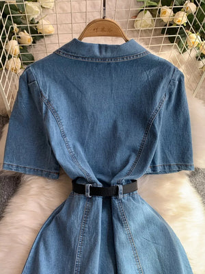 Light blue denim collared dress with short sleeves and a black belted waist.