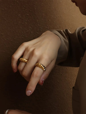 Gold sculpted steel croissant ring with twisted band detail.