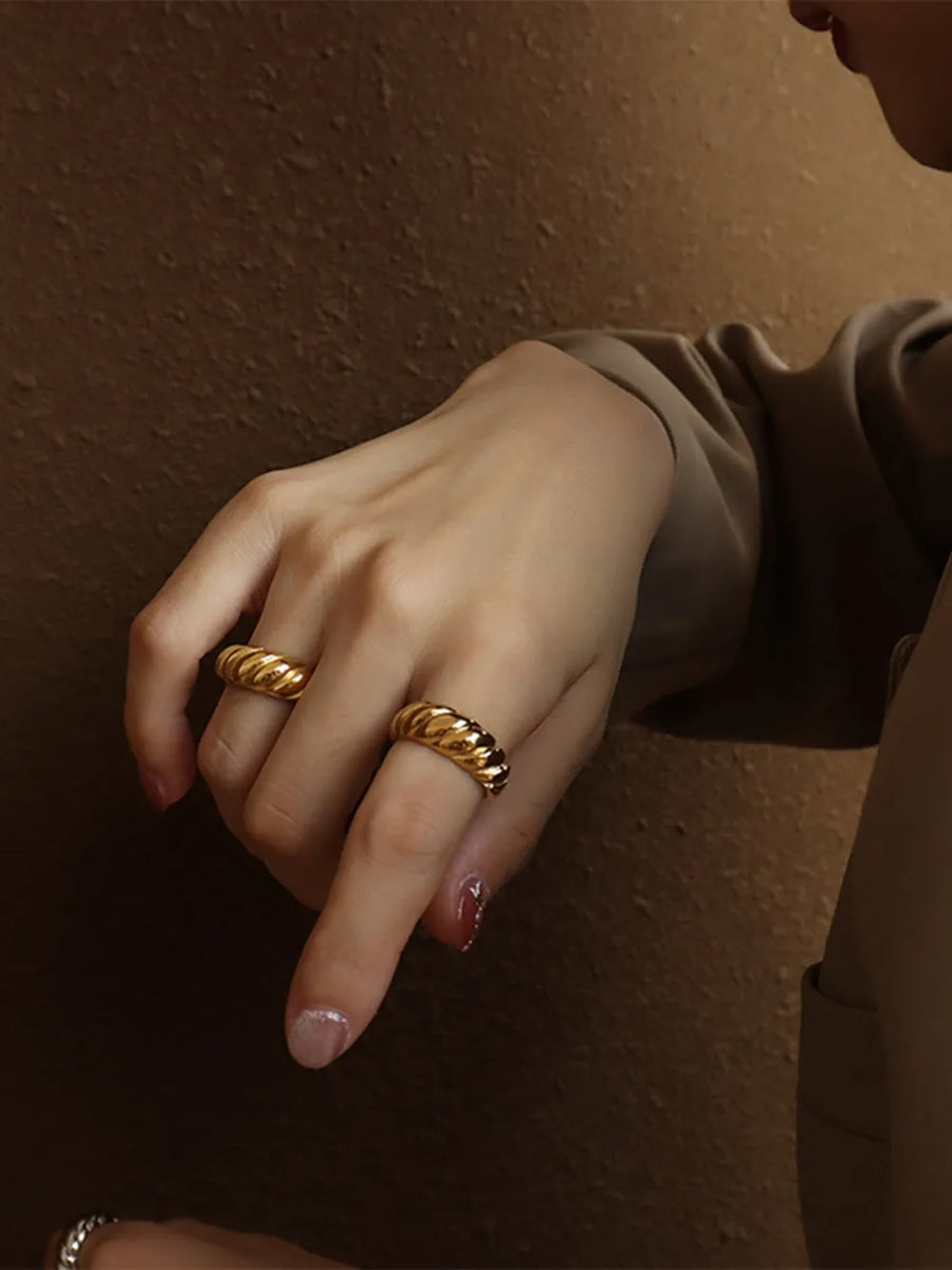 Gold sculpted steel croissant ring with twisted band detail.