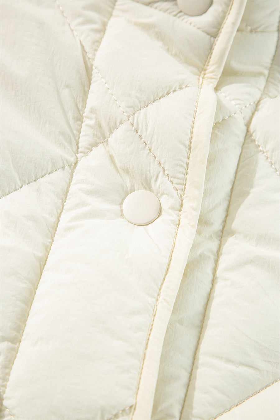 Ivory quilted vest with diamond stitching and a snap closure detail.