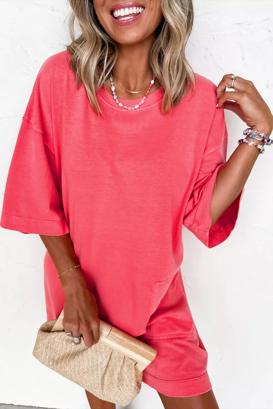 Coral cotton blend t-shirt mini dress with crew neck and drop shoulders, styled with a clutch.