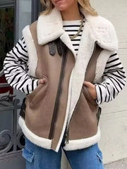 Brown faux shearling vest coat with a zip front, shearling collar and trim, styled over a striped top.