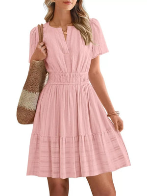 Pink textured V-neck tiered dress with smocked waist and short sleeves.