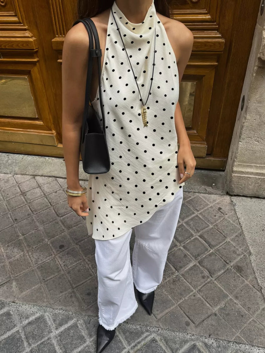 Cream polka dot halter top with asymmetrical hem, paired with white frayed jeans and black pointed heels.