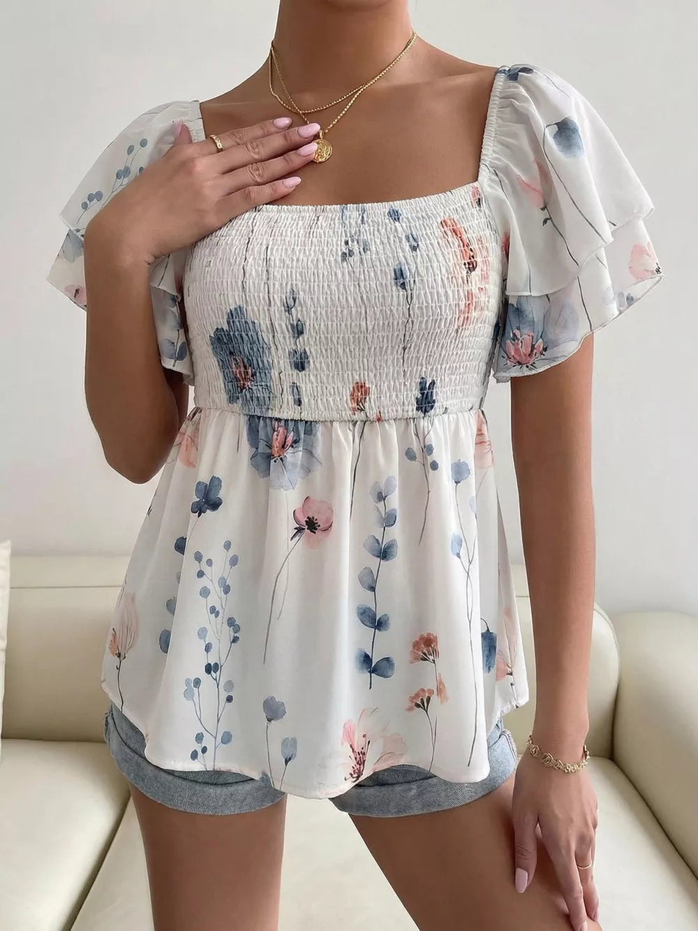 Smocked square neck blouse with flutter sleeves and a floral print.