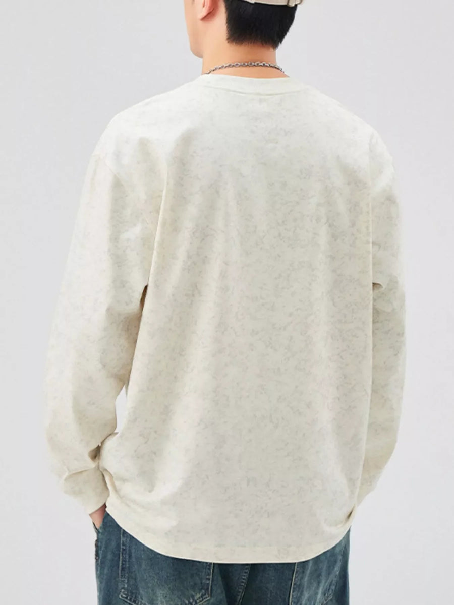 Oversized long-sleeve tee in light apricot with a subtle all-over pattern.
