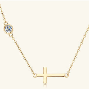 Gold asymmetrical cross pendant necklace with a single bezel-set crystal accent.