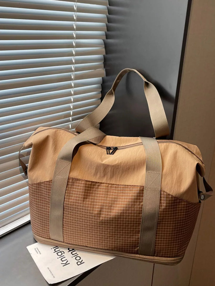 Spacious nylon travel duffel bag in tan with a checkered lower panel and tan straps.