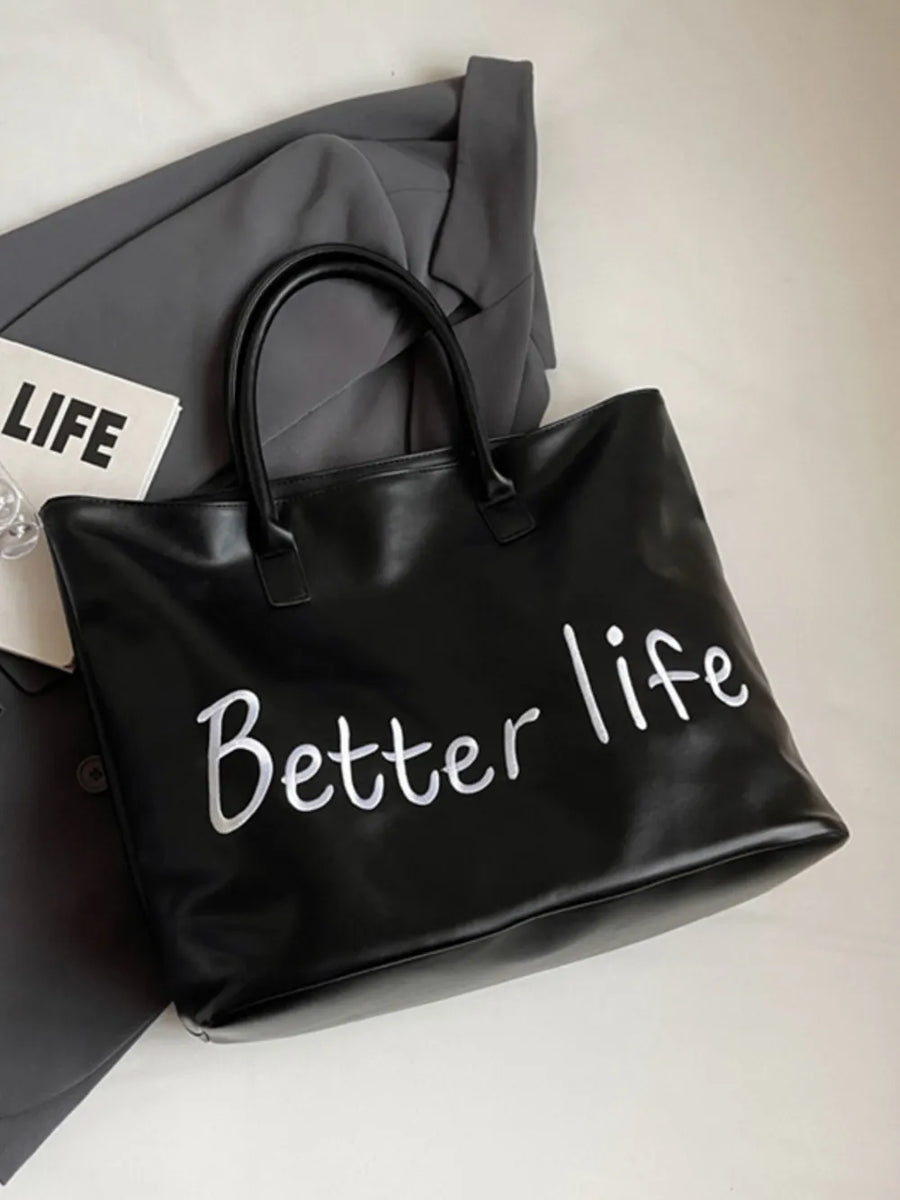 Black tote bag with white metallic "Better Life" graphic and double handles.