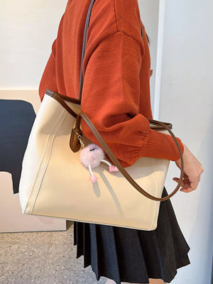 Beige PU leather tote bag with brown trim and a fluffy pink charm.