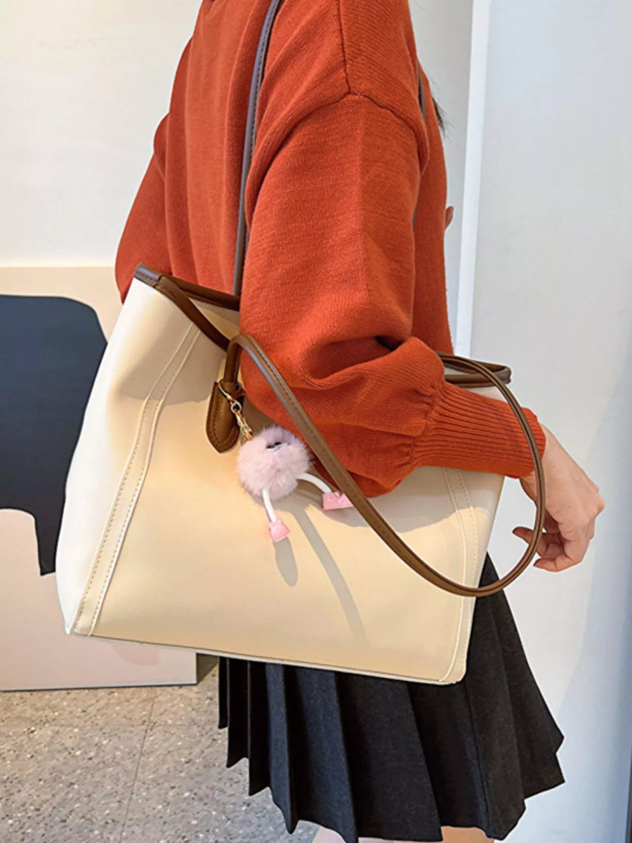 Beige PU leather tote bag with brown trim and a fluffy pink charm.