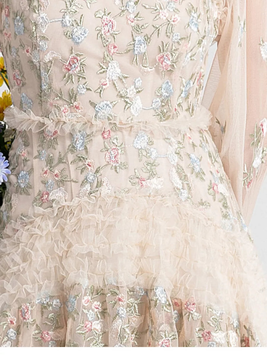 Embroidered floral tulle maxi gown with ruffled tiers and sheer sleeves.