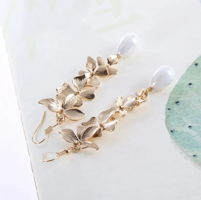 Gold cascading flower drop earrings with white pearl accents.