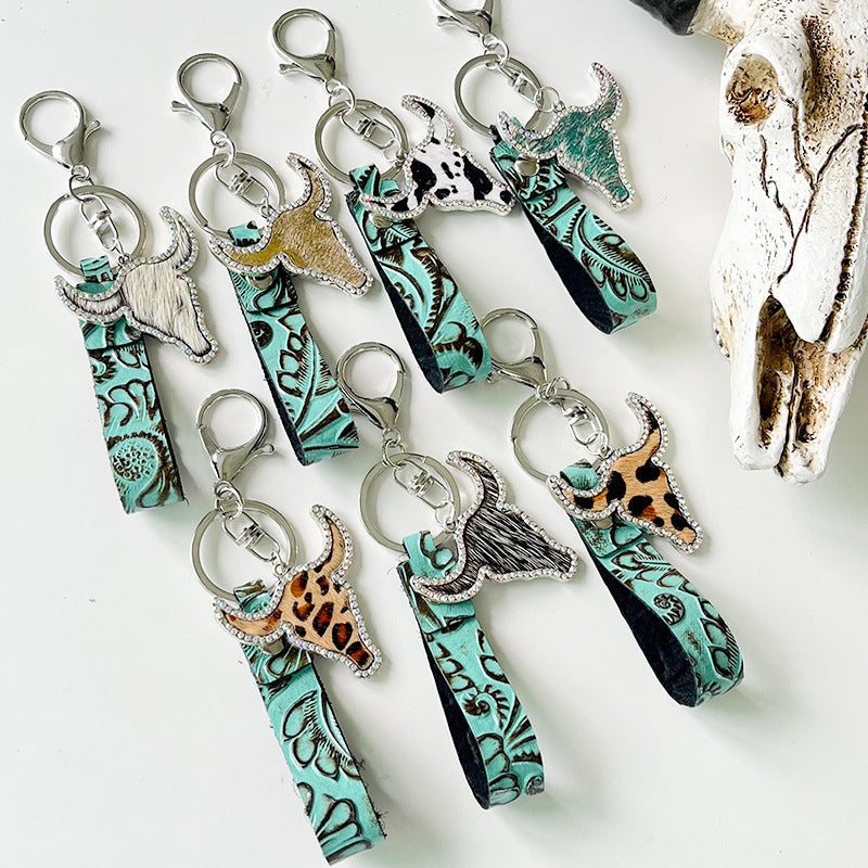 Embossed leather bull keychains with crystal accents in various animal prints and turquoise.