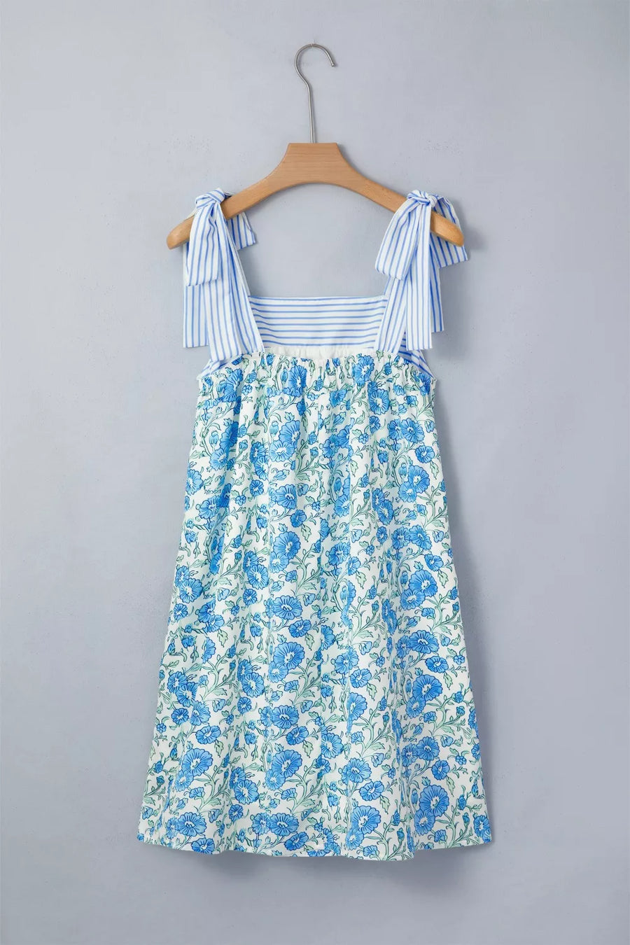 Botanical print mini dress with tie straps and blue stripes on bodice.