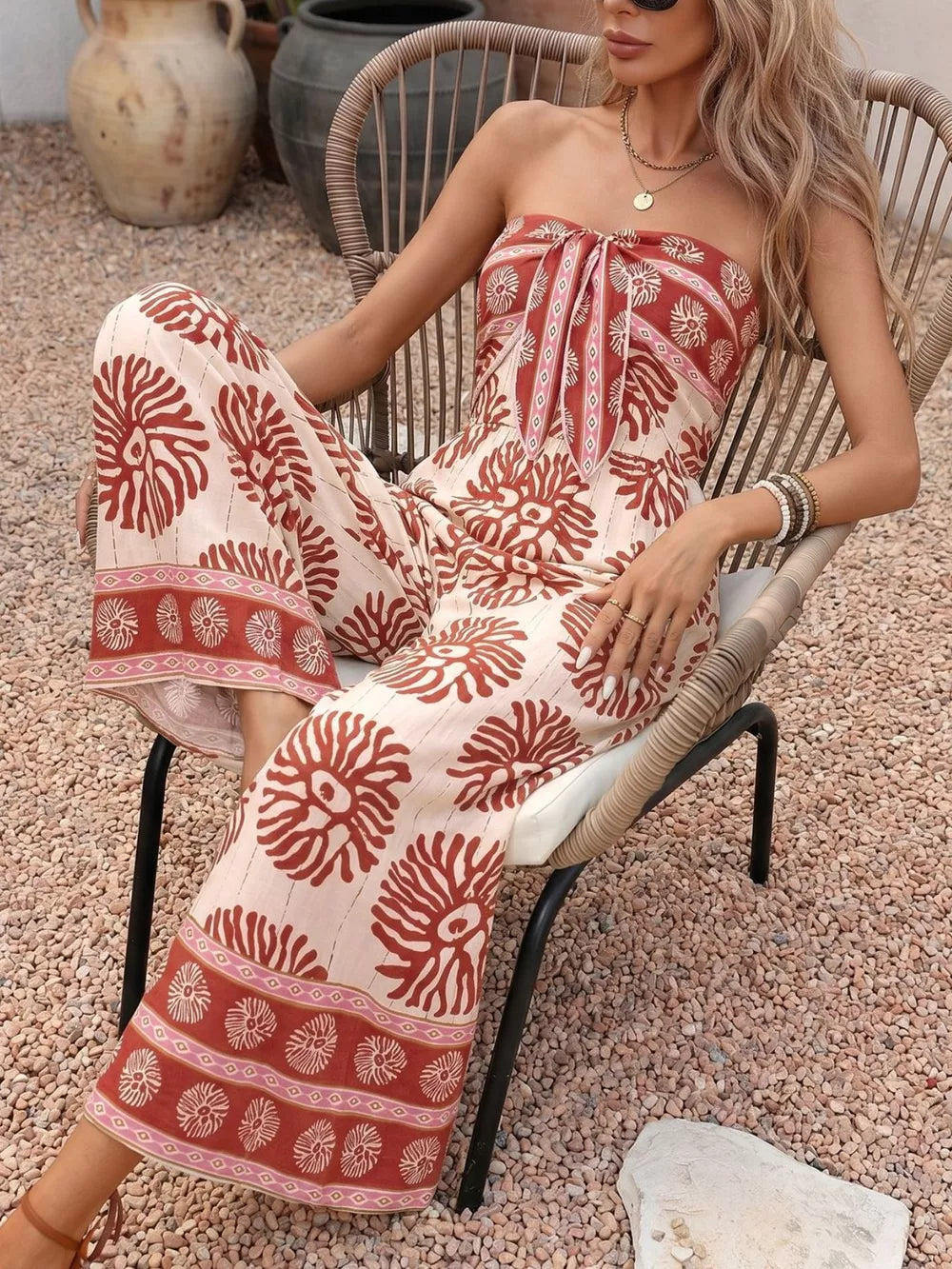 Floral tie-front wide-leg romper in cream with rust print, strapless neckline, and wide legs.
