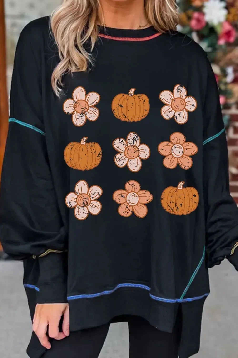 Black sweatshirt with floral and pumpkin print, contrast stitching, and crew neck.