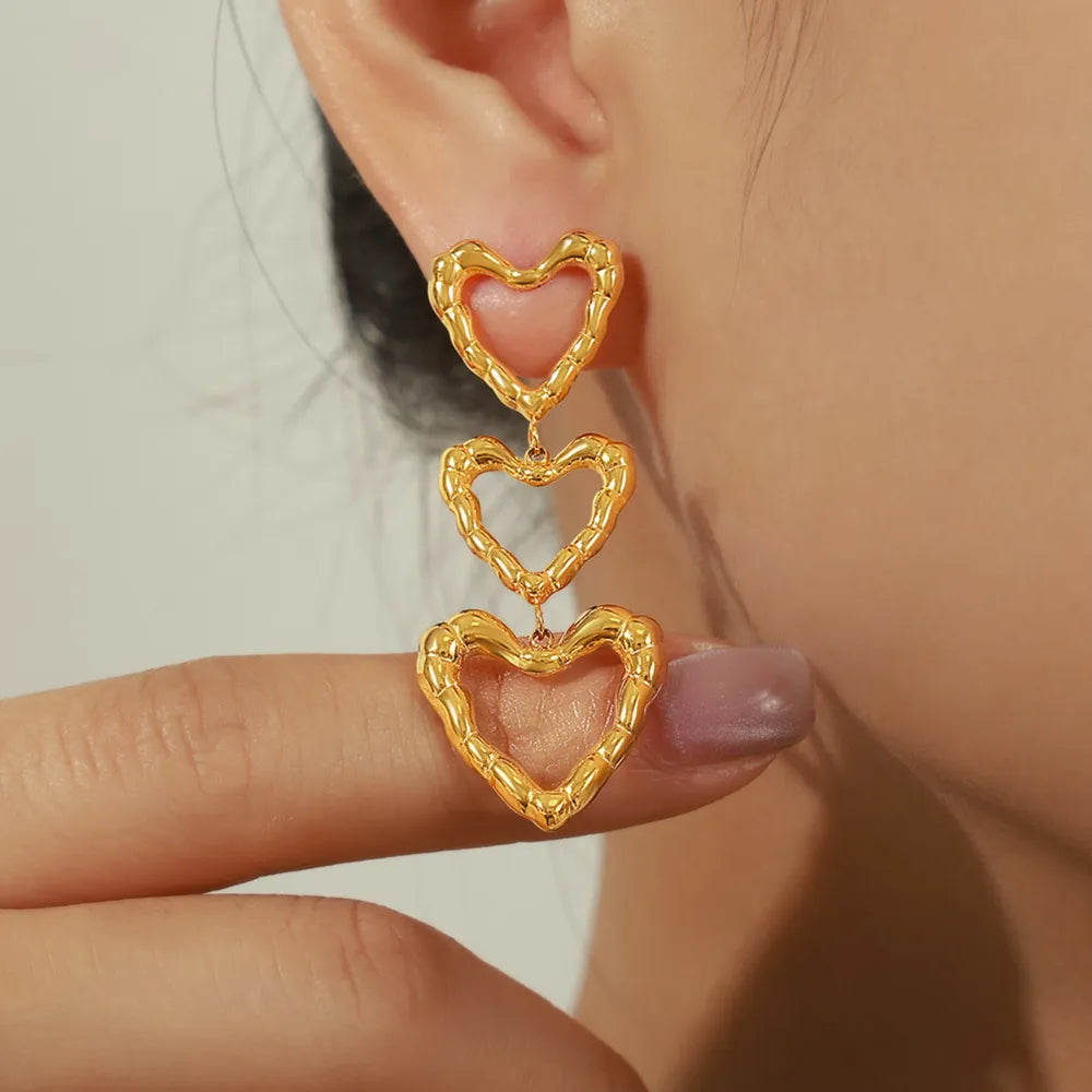 Gold triple heart drop earrings with textured detail