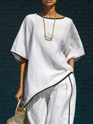 White two-piece set with contrast trim, featuring a relaxed top and cropped pants.