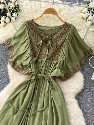 Mint green bohemian maxi dress with V-neck, tie front, embroidered details, and flutter sleeves.