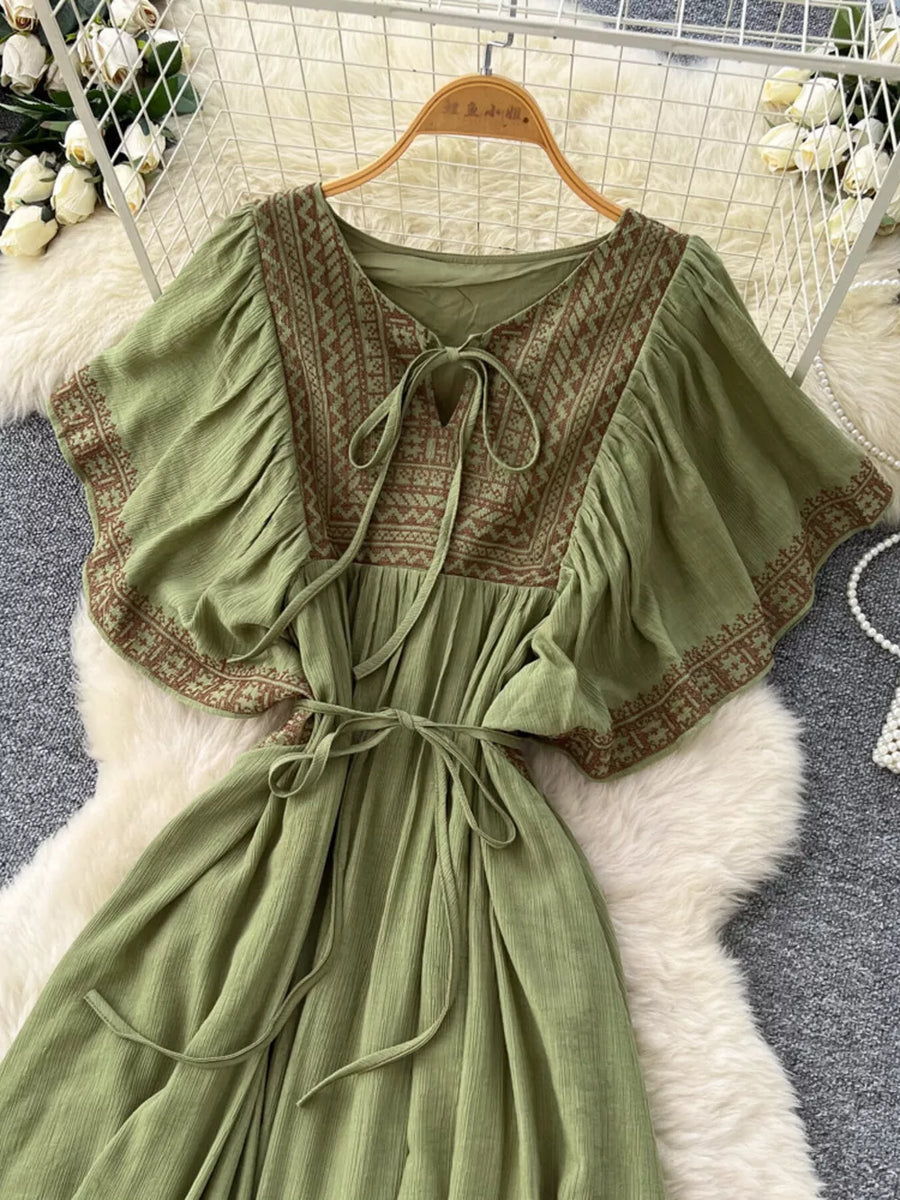 Mint green bohemian maxi dress with V-neck, tie front, embroidered details, and flutter sleeves.