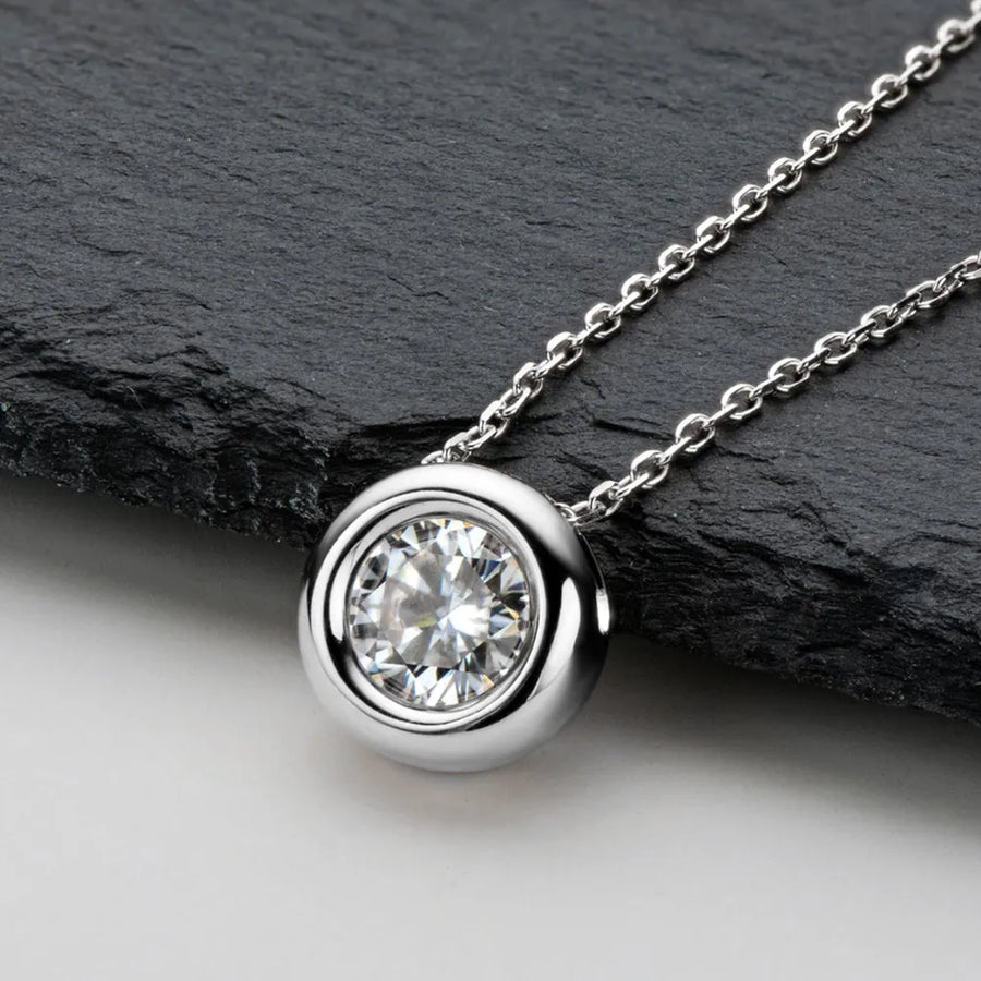 Silver solitaire pendant necklace with bezel-set clear stone on a delicate chain.