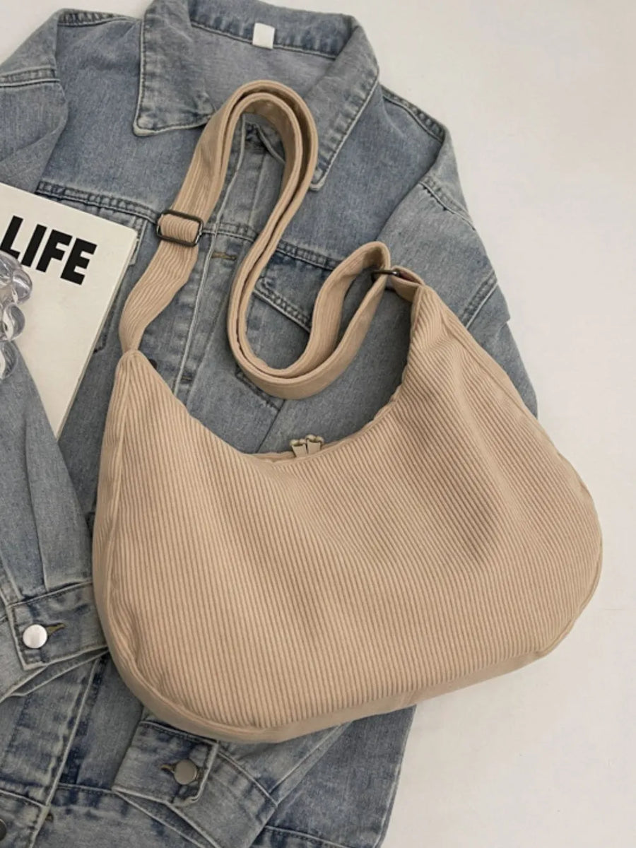 Beige corduroy crescent shoulder bag with adjustable strap and zipper closure.