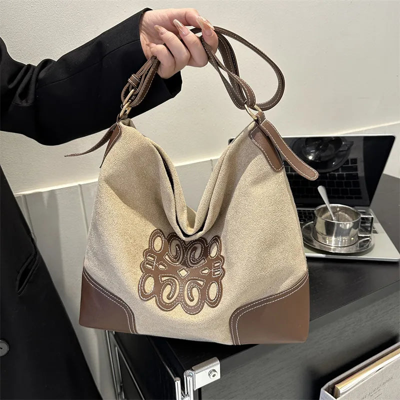 Khaki suede hobo bag with brown leather trim and contrast stitching.
