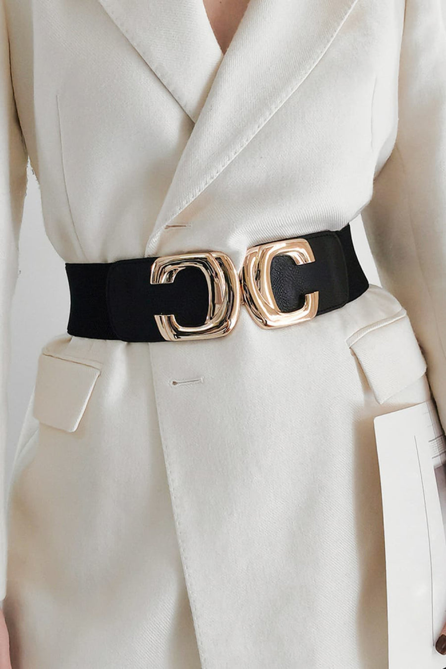 Black elastic waist belt with double C gold buckle styled over a cream blazer.