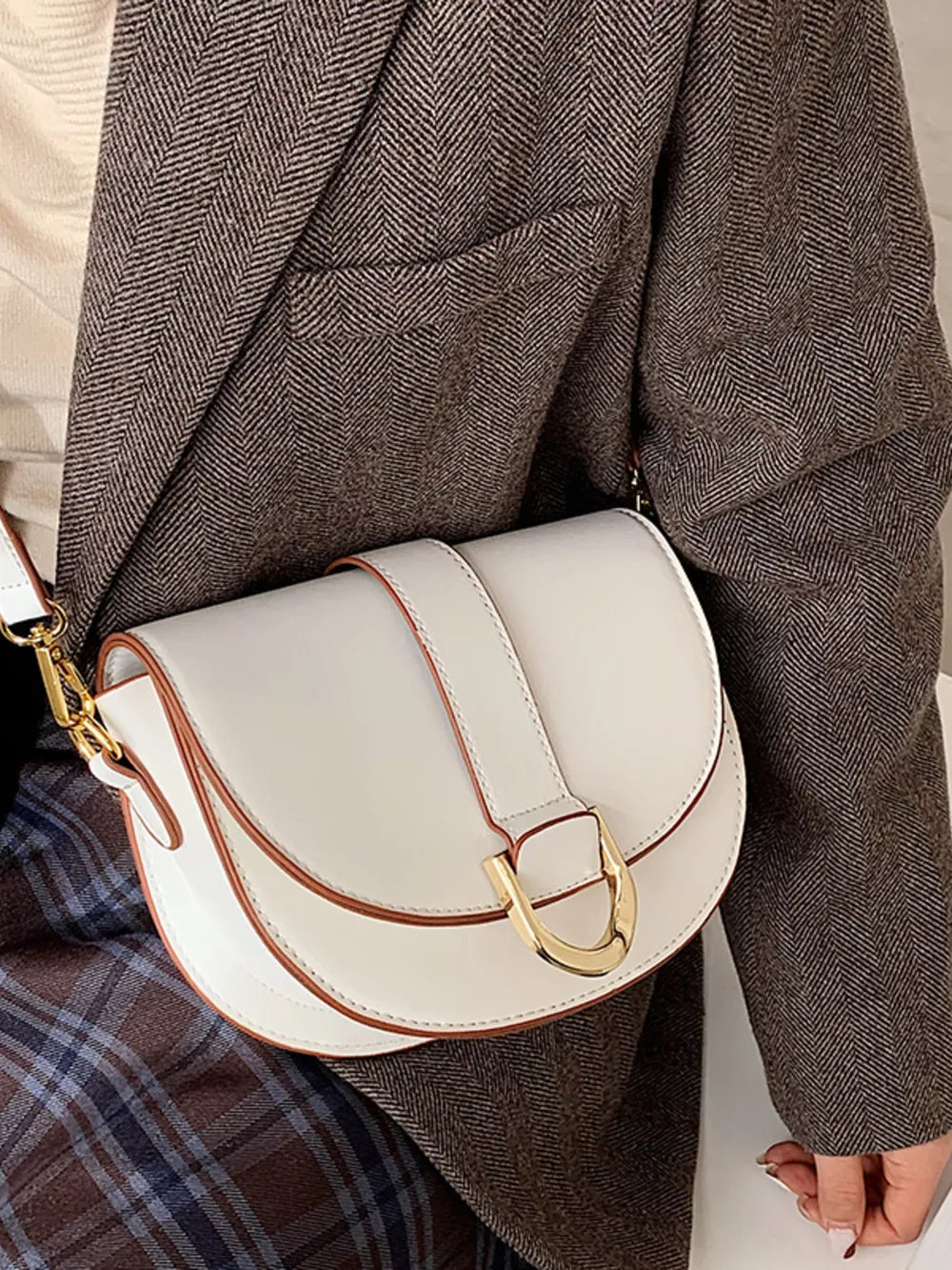 Chic white semi-circular flap crossbody bag with gold hardware and brown trim.