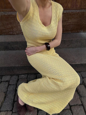 Yellow knit midi dress with scoop neck and side slit, styled with a bracelet.