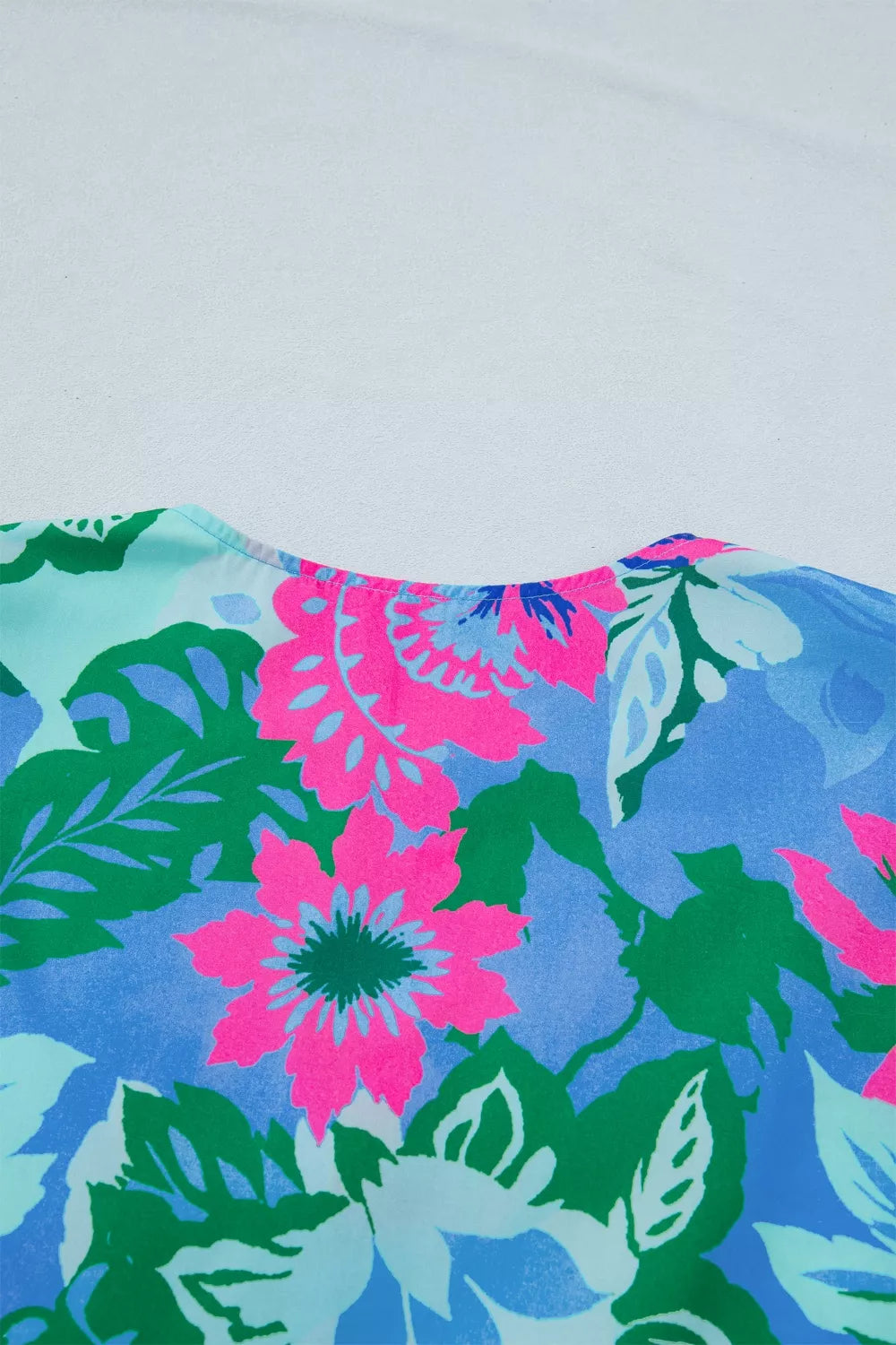 Vibrant floral v-neck blouse with pink, blue, green, and light blue flowers and leaves.