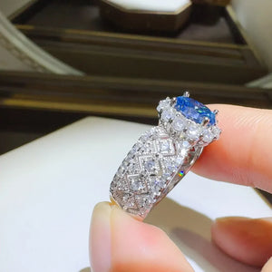 Silver ring with blue moissanite and zircon halo and diamond pattern band